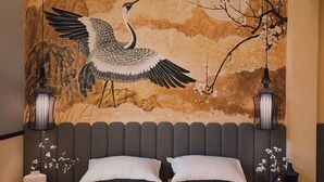 Een slaapkamer met een groot bed, twee nachtkastjes en een wanddecoratie van een kraan.