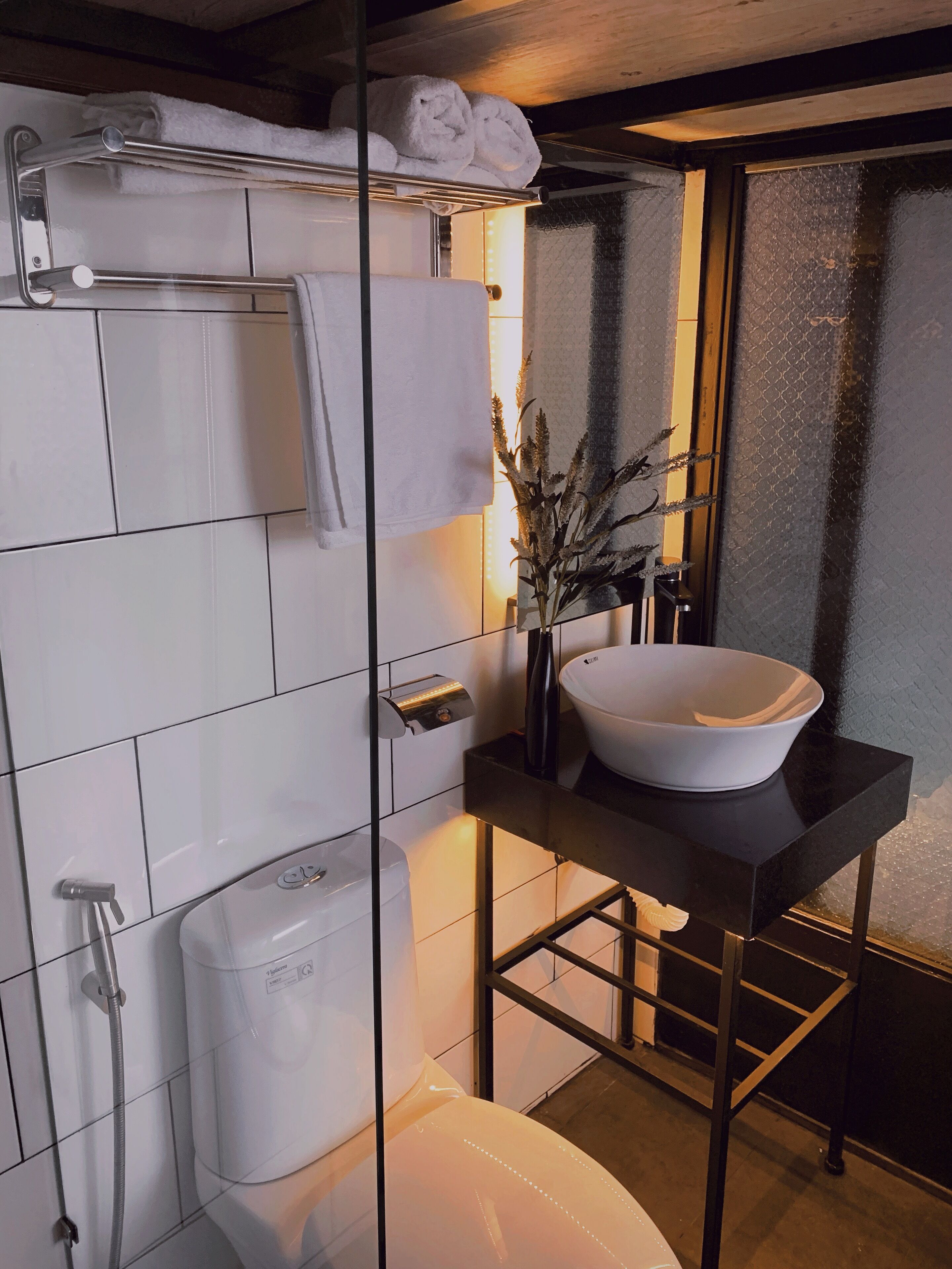 A modern bathroom with a glass-enclosed shower, a white sink, and a towel rack.