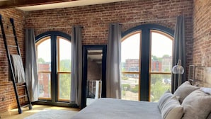 Une chambre avec un grand lit, une échelle et une vue sur l’extérieur grâce à des fenêtres en arc de cercle.