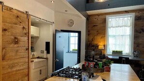 Une cuisine avec un îlot central en bois, une cuisinière, des placards et une fenêtre avec des rideaux.
