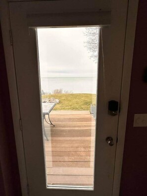 A door with a view of a wooden deck and a table outside.