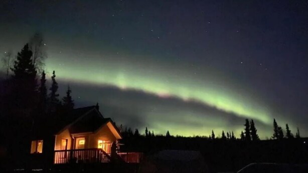 Ein Haus mit Veranda und Blick auf das Nordlicht.