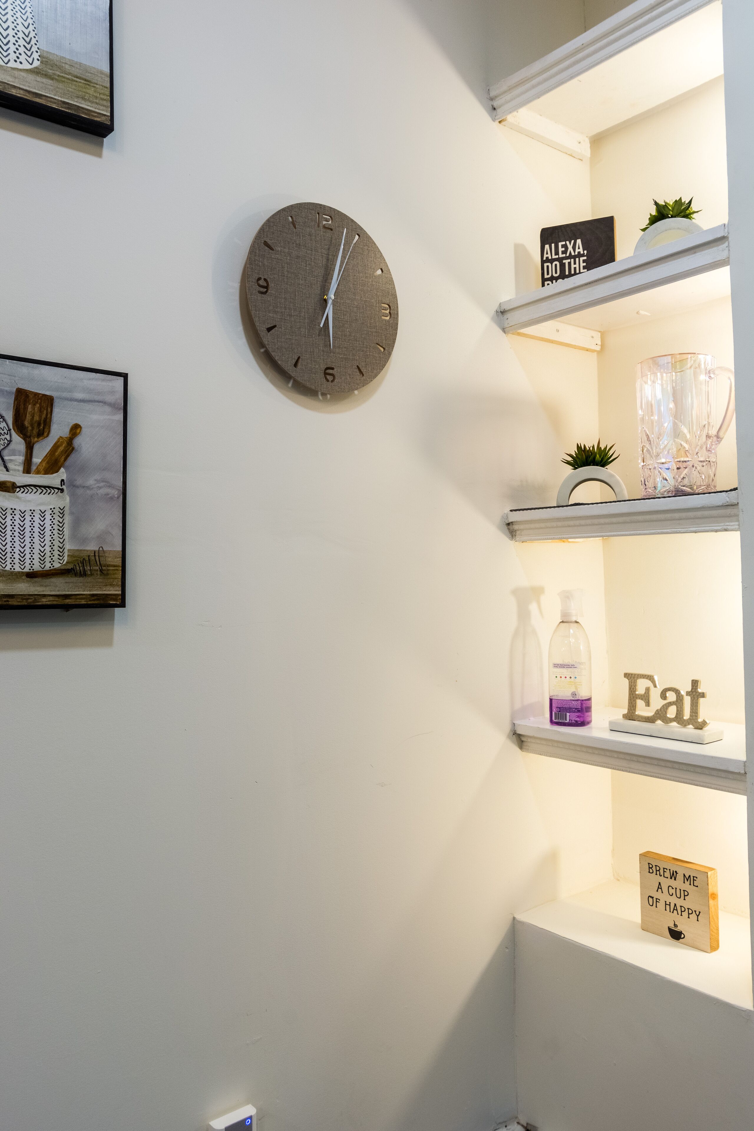 A wall with a clock, shelves with decorative items, and a framed picture.