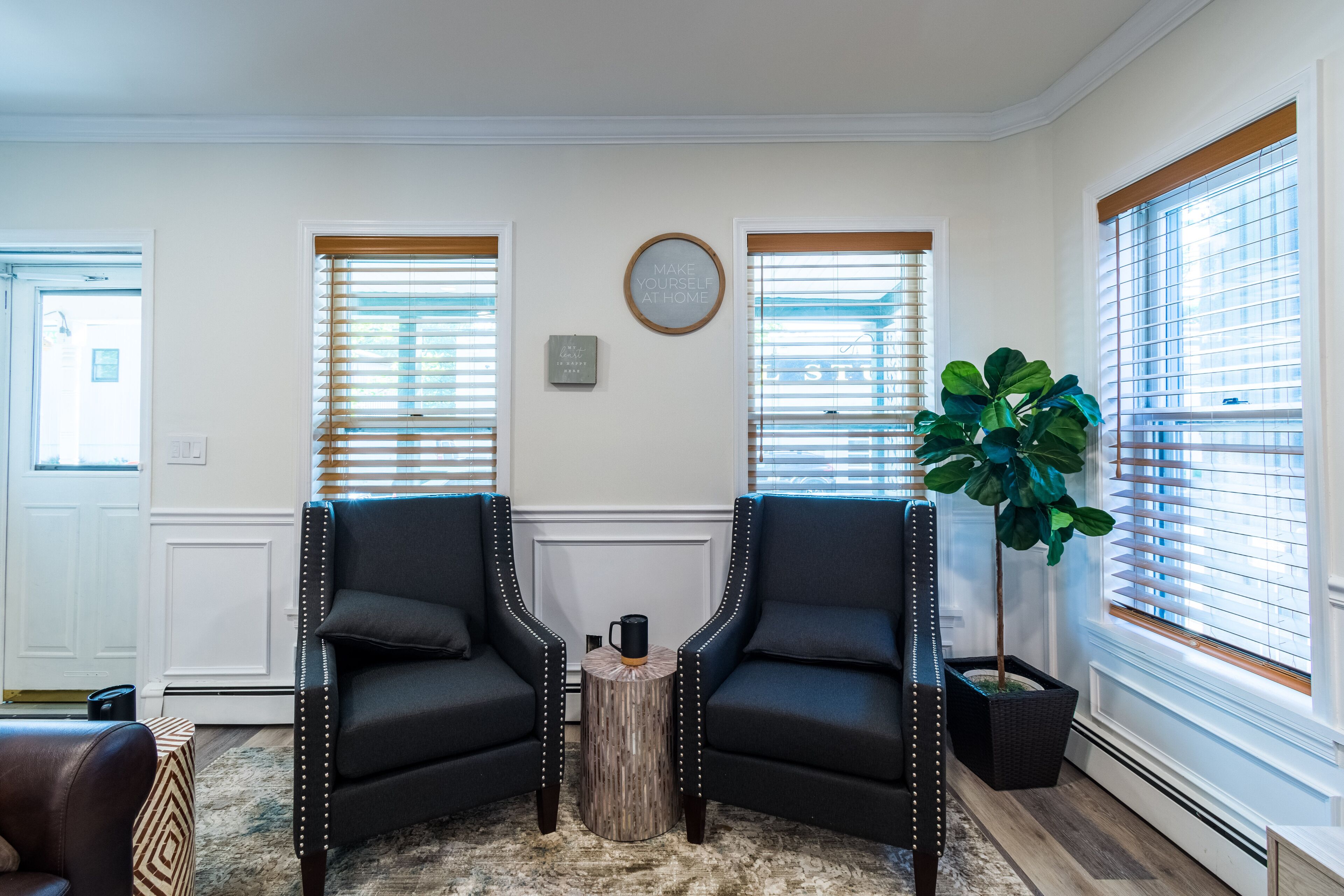 A living room with two black leather armchairs, a small wooden coffee table, and a potted plant.