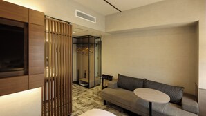 A modern hotel room with a sofa, a small round table, a TV, a wardrobe, and a mirror. - SK HOTEL KOBE STATION FRONT (Kobe)