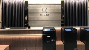 A modern hotel reception desk with a logo, a digital kiosk, and a coffee machine. - SK HOTEL KOBE STATION FRONT (Kobe)