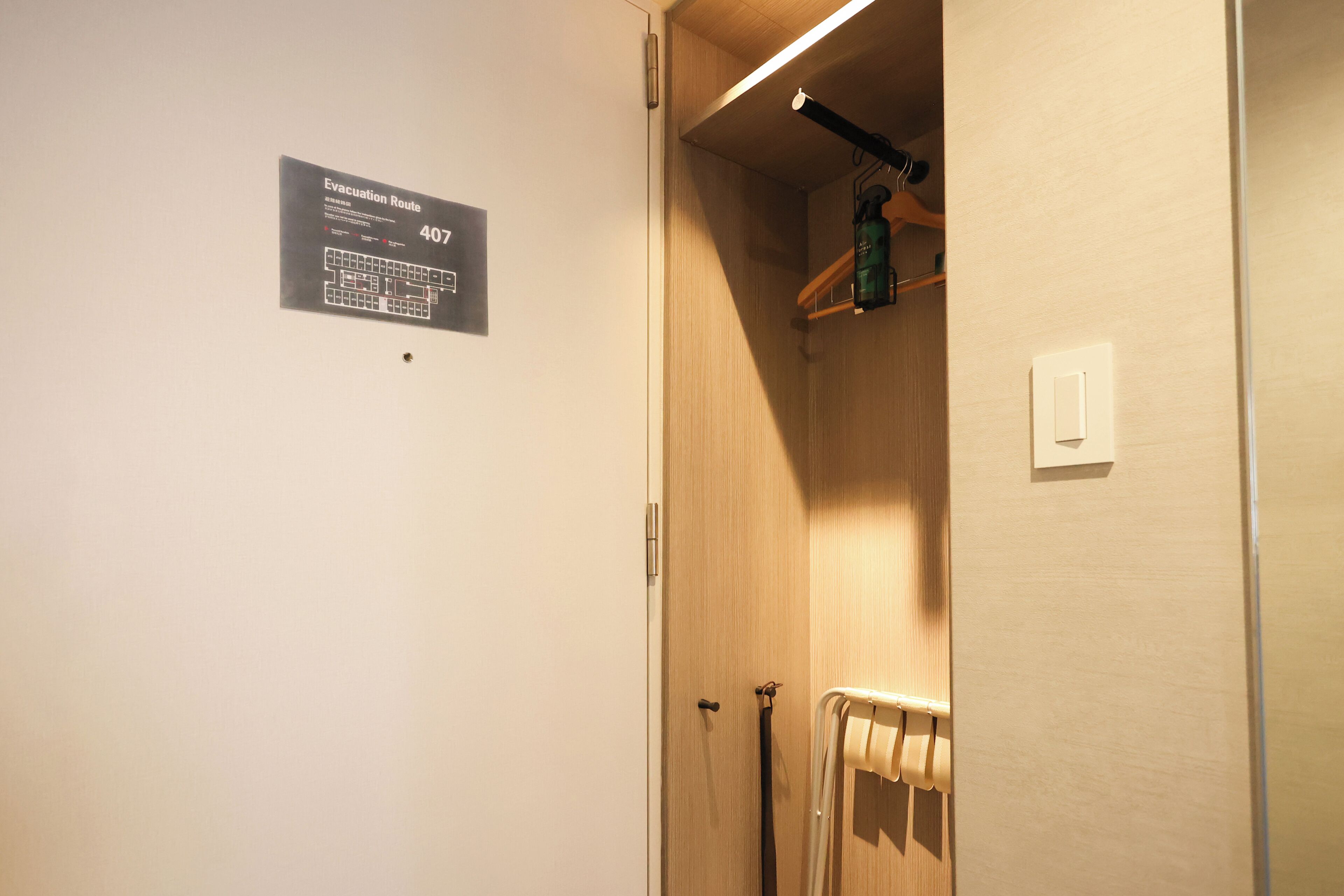 A room with a wooden door, a towel rack, and a shelf with a water bottle.