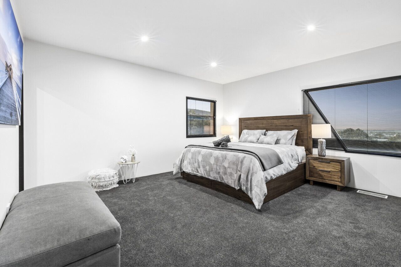 A modern bedroom with a large bed, a nightstand, a small table, and a window with a view.