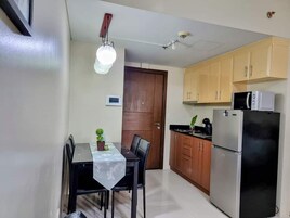 A compact kitchen with a refrigerator, microwave, and wooden cabinets.