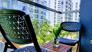 A balcony with two chairs and a small table, a potted plant, and a view of high-rise buildings. - One Palm Tree Villas - Unit 3i and 3j (Pasay)