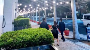 A nighttime street with string lights, a sidewalk, and a building with multiple windows. - One Palm Tree Villas - Unit 3i and 3j (Pasay)