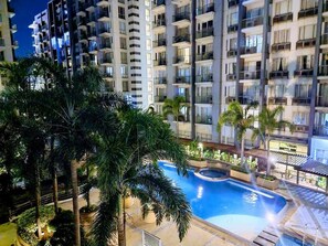A high-rise residential building with multiple balconies, a swimming pool, and surrounding palm trees. - One Palm Tree Villas - Unit 3i and 3j (Pasay)