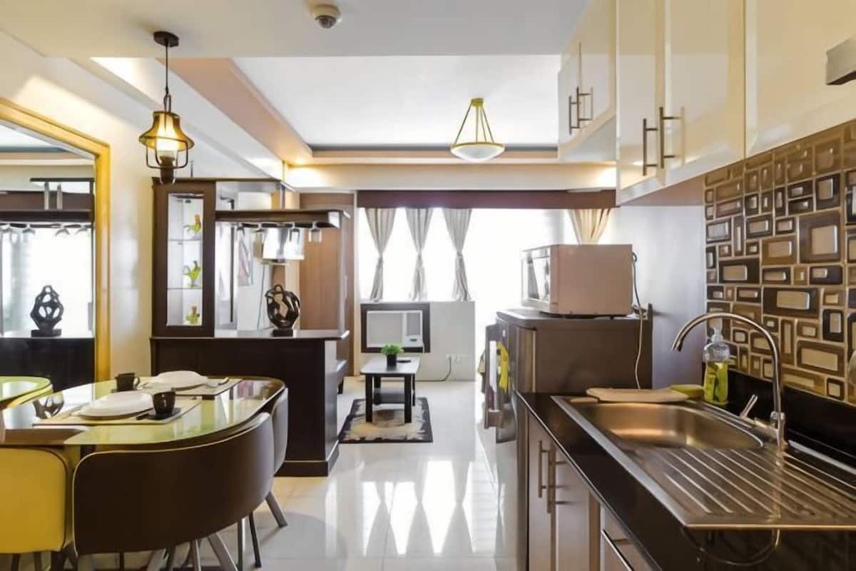 A modern kitchen with a dining area, a built-in oven, and a large window with curtains.