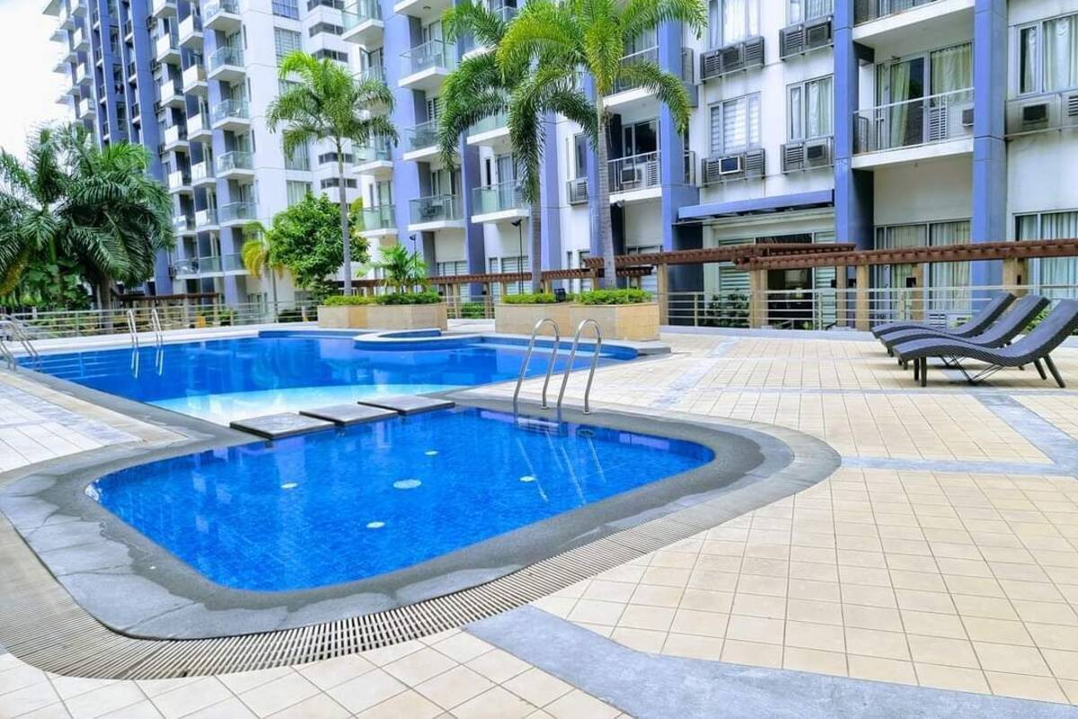 A swimming pool with a tiled deck, surrounded by palm trees and lounge chairs.