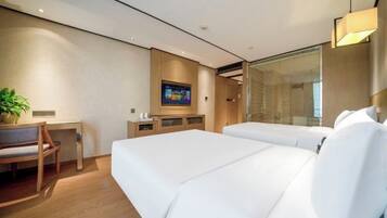 Habitación de hotel moderna con dos camas, un escritorio, una silla, un televisor y un ventanal grande.