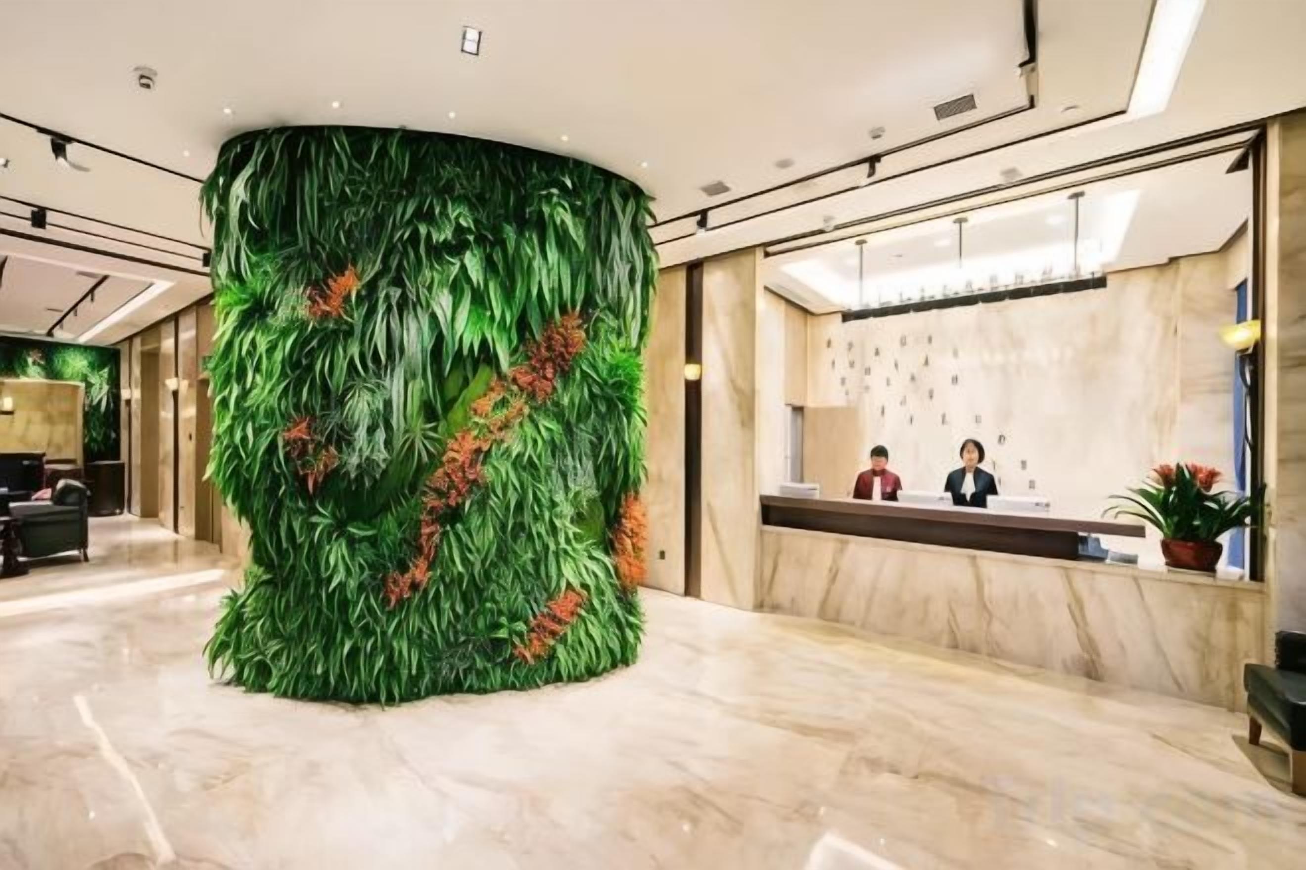 A reception area with a large green wall feature, a marble floor, and a reception desk.