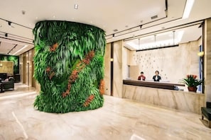 A reception area with a large green wall feature, a marble floor, and a reception desk. - Xierdun Yixuan Hotel (Lishui)