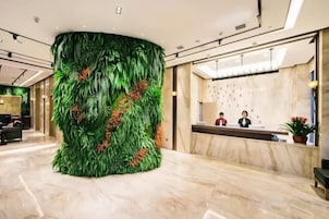 Un área de recepción con una gran pared verde, suelo de mármol y mostrador de recepción.