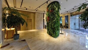 A lobby with a large artificial green wall, marble flooring, and potted plants. - Xierdun Yixuan Hotel (Lishui)