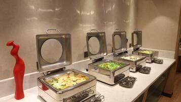 A buffet setup with multiple food dispensers and utensils.