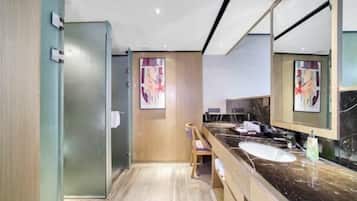 A modern bathroom with a large mirror, a marble countertop, and a wooden chair.