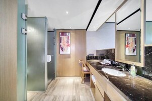 Un baño moderno con un espejo grande, encimera de mármol y una silla de madera.