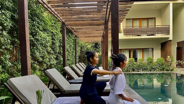 A spa area with a pool, lounge chairs, and a massage table. - Siemreap Vasinh Residence (Siem Reap)