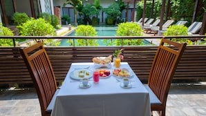 A dining table set with breakfast items, overlooking a pool and lounge area. - Siemreap Vasinh Residence (Siem Reap)