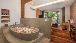 A modern bathroom with a stone bathtub, wooden flooring, and a view of the outdoors. - Siemreap Vasinh Residence (Siem Reap)