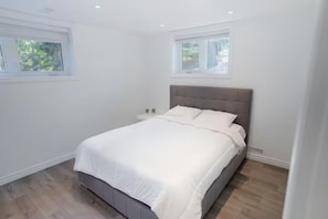 Un dormitorio con una cama, dos mesitas de noche y una ventana.