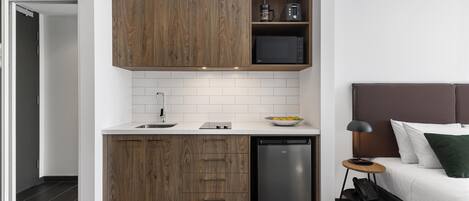 A compact kitchen with wooden cabinets, a microwave, and a dishwasher.