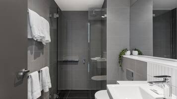 Une salle de bain moderne avec une douche à parois de verre, un lavabo blanc et un grand miroir.