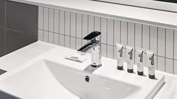 A bathroom sink with a modern faucet and five tubes of milk shampoo and conditioner.