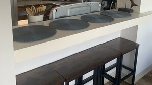 Eine moderne Küche mit Holzausstattung, einer zentralen Kochinsel mit Barhocker und einer Mikrowelle.
