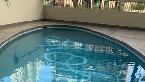 Ein Schwimmbecken mit einer gefliesten Kante und einer Metallleiter.