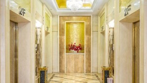 A hotel lobby with a checkered floor, a chandelier, and a wall with a golden pattern. - Luanzhou International Hotel (Luanzhou)