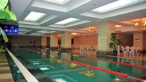 An indoor swimming pool with clear lanes, a ceiling with skylights, and a reception area with chairs and a plant. - Luanzhou International Hotel (Luanzhou)