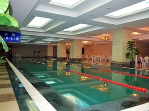 A swimming pool with lane dividers, a ceiling with recessed lighting, and a sign with text.
