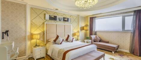 A hotel room with a large bed, a bench, a bedside table, a nightstand, a chandelier, and a window with curtains.
