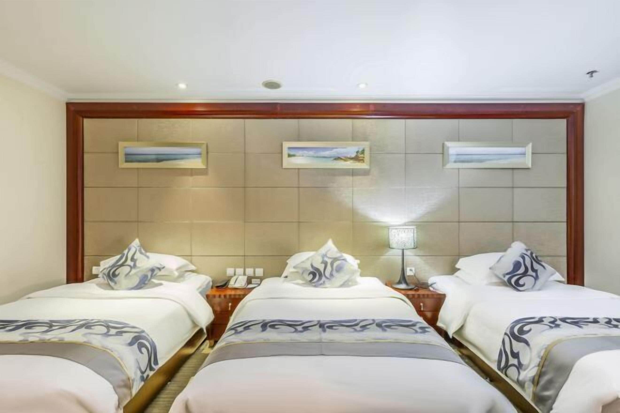 A hotel room with two beds, a wooden headboard, and three framed pictures on the wall.