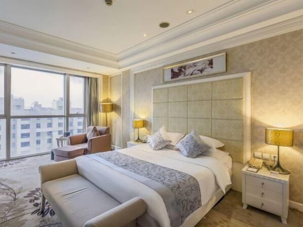 A hotel room with a large bed, a nightstand, a chair, and a view of the city. - Luanzhou International Hotel (Tangshan)