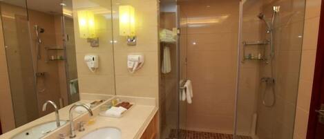 Un baño moderno con un espejo grande, lavamanos dobles, cabina de ducha de vidrio y suelo de ducha con azulejos.