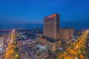 Ein Hochhaus-Hotel mit auffälliger Beschilderung, umgeben von einem gut beleuchteten Stadtgebiet mit Straßen und weiteren Gebäuden.