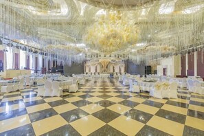 A large hall with a checkered floor, white chairs, and a central stage. - Luanzhou International Hotel (Luanzhou)