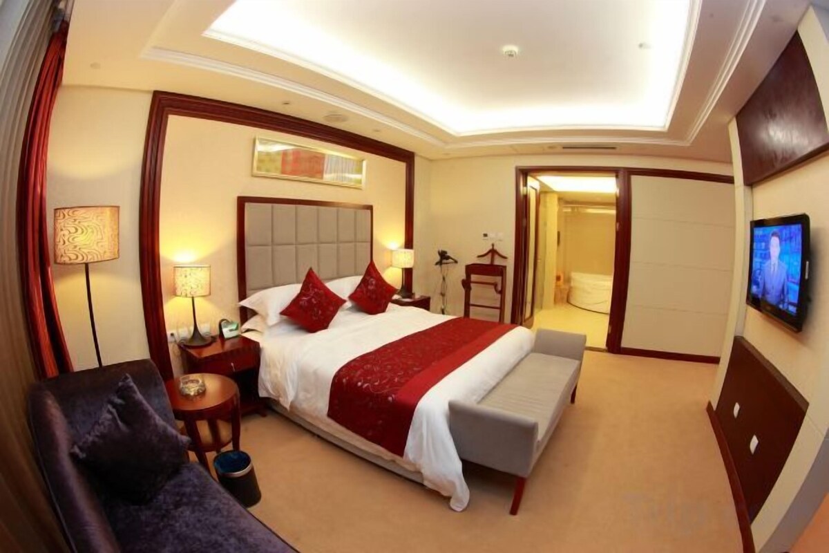 Una camera d'albergo con un letto grande, comodini, una TV e un angolo relax.