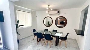 Un comedor moderno con una mesa de vidrio, sillas azules y un suelo de mármol.