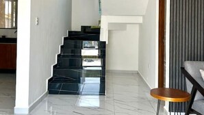 Un interior moderno con una escalera, un área de comedor y una cocina al fondo.