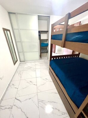 Una habitación con literas, un armario con puerta corredera y suelo de baldosas.