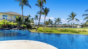 A resort with a swimming pool, palm trees, and a view of the ocean.