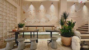 A modern interior with a central seating area, a wall with embossed artwork, and a staircase. - YLUNA Boutiquestay (Can Tho)